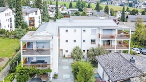 Un edificio residencial de varios pisos con balcones, un patio cubierto y un jardín.