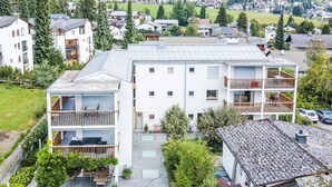 A multi-story residential building with balconies, a covered patio, and a garden area.