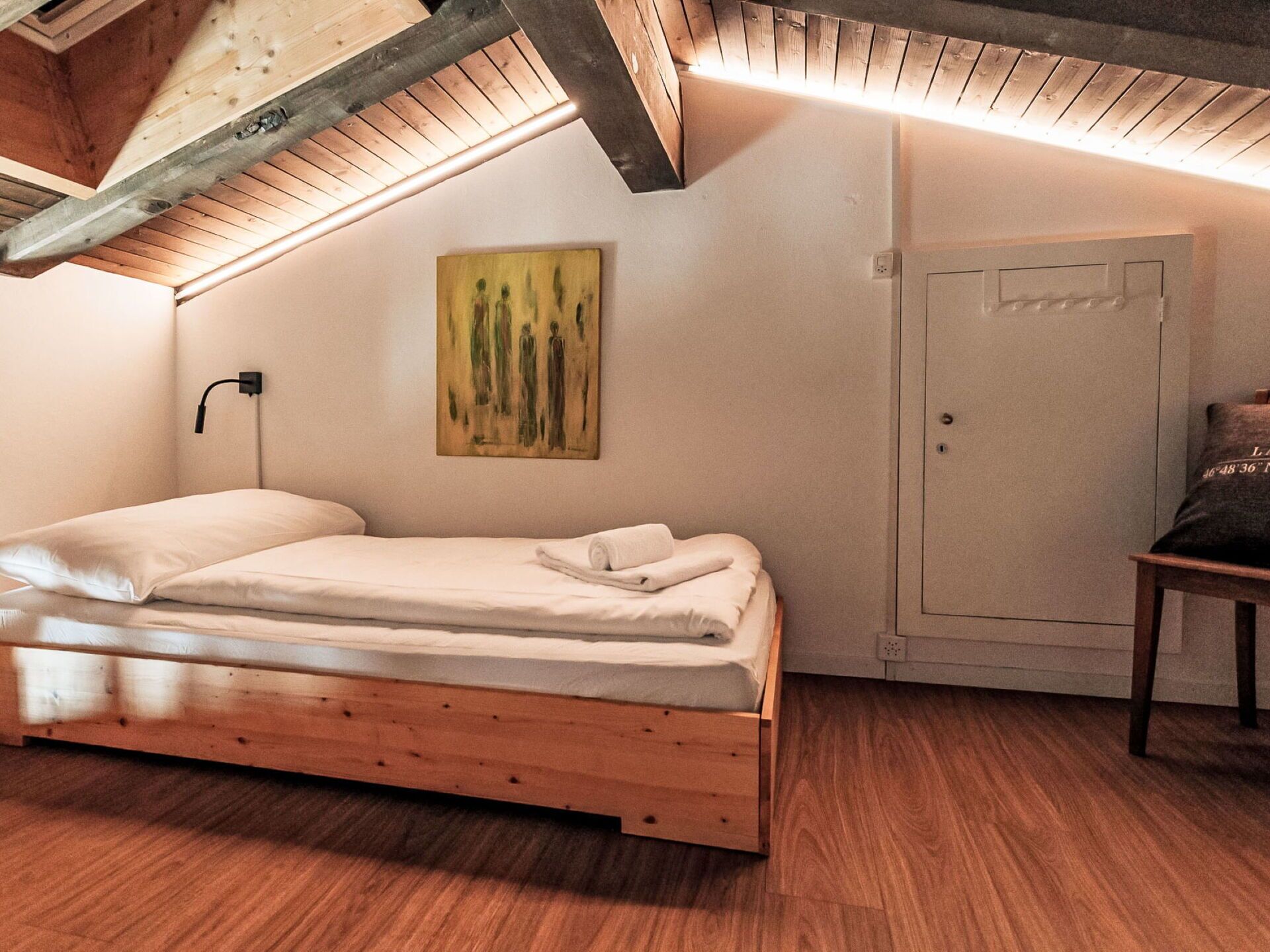 Ein Schlafzimmer mit einem hölzernen Bett, einem Bild an der Wand und einer Tür mit Schloss.