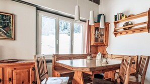 A wooden dining table with chairs, a cabinet, and pendant lights.