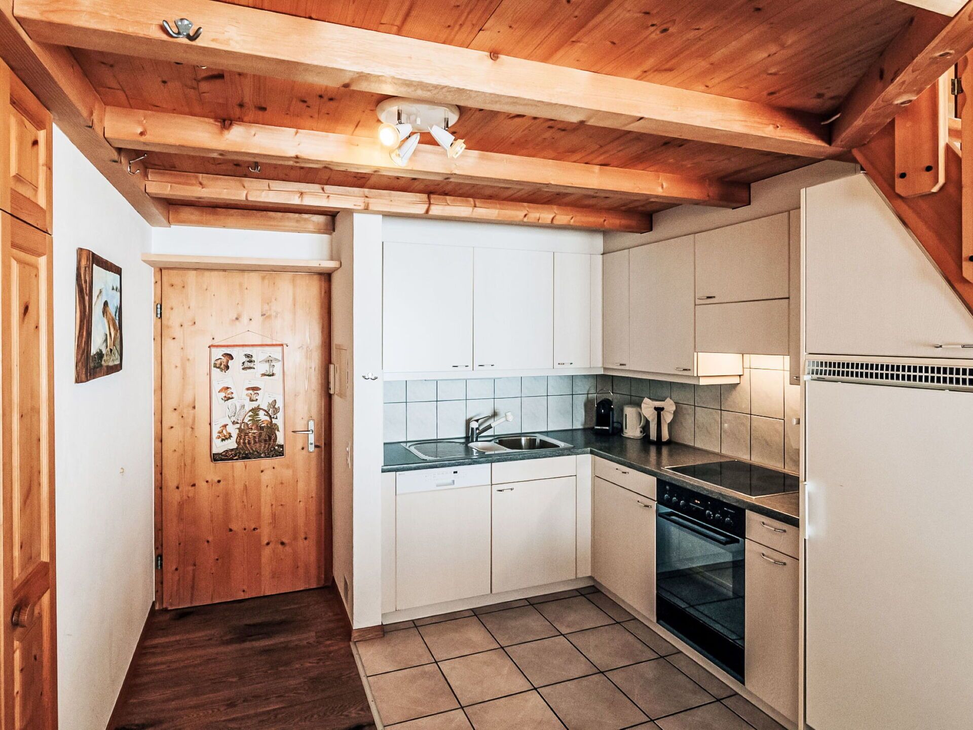 Eine kleine Küche mit weißen Schränken, einer Spüle, einem Herd und einem Kühlschrank.