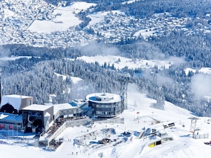 A ski resort with a modern building, ski lifts, and a snowy landscape.