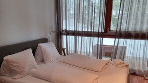 Una cama doble con cabecera de madera, una mesita de noche y una ventana con cortinas.