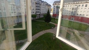 Näkymä ikkunasta sisäpihalle, jossa on rakennuksia, käytävä ja puu.