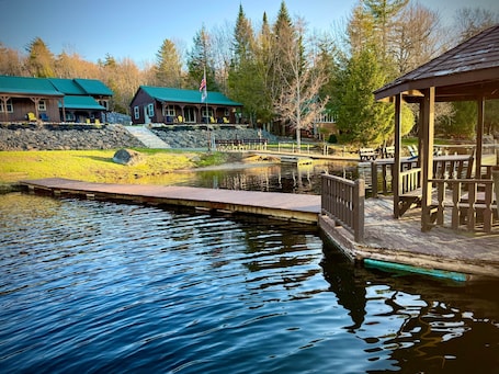 A lakeside lodge with a dock, a covered seating area, and a stone wall.. Cedar - Big Moose Lakeside