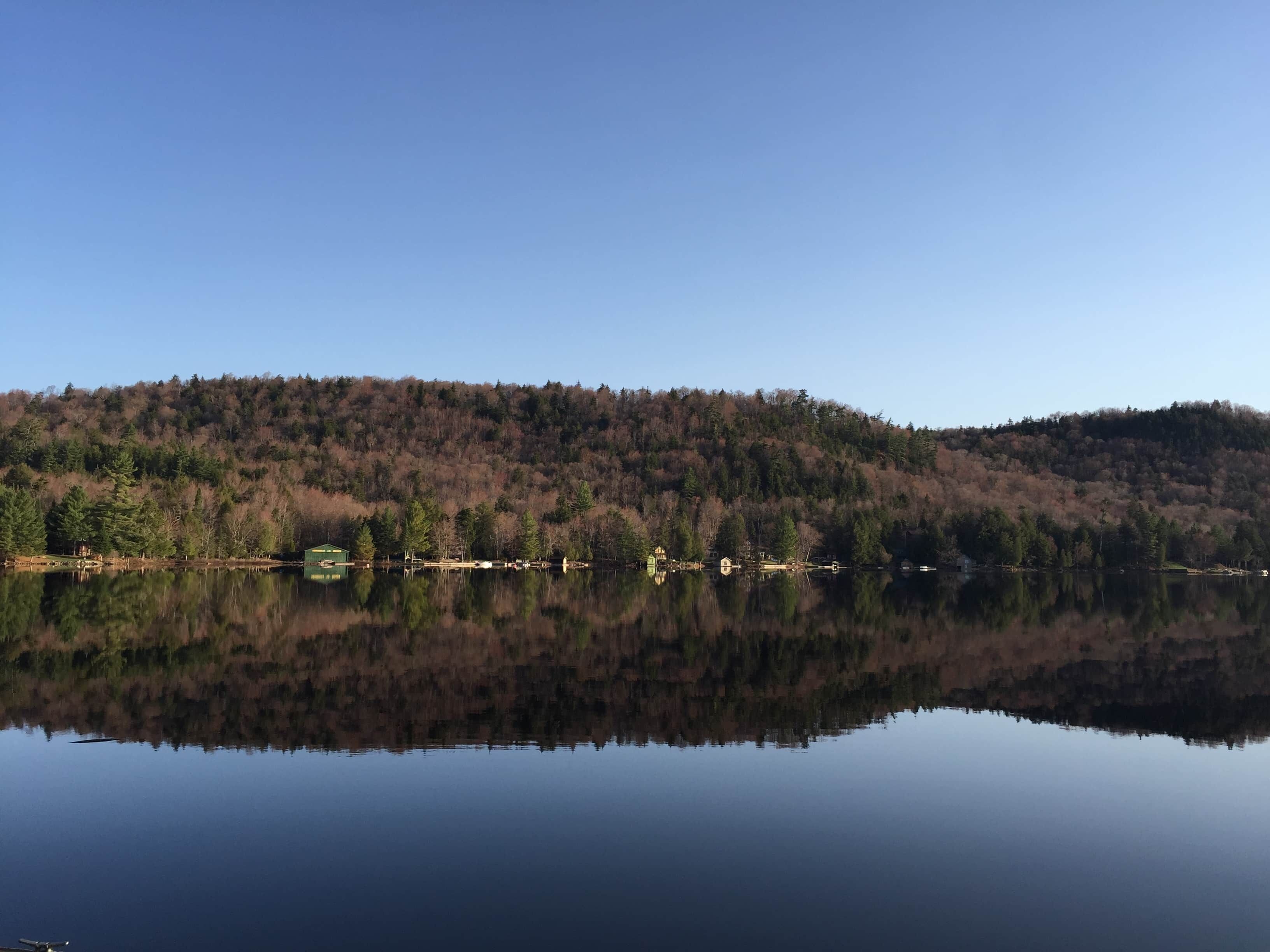 Ein ruhiger See mit bewaldeter Hanglandschaft im Hintergrund.