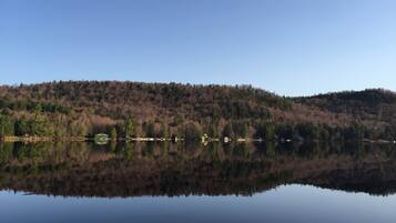 Ein ruhiger See mit bewaldeter Hanglandschaft im Hintergrund.