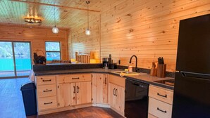 A modern kitchen with wooden cabinets, a black dishwasher, and a black refrigerator. - Deer Run - Big Moose Lakeside (Eagle Bay)