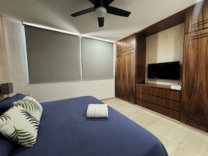 Ein Schlafzimmer mit Bett, Fernseher, Deckenventilator und Kleiderschrank.