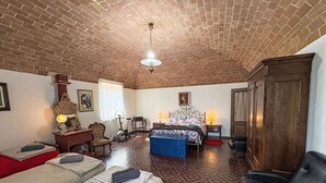Une pièce avec un plafond en briques, un lit, un bureau, une chaise et une armoire.