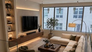 A modern living room with a large TV, comfortable seating, a coffee table, and a staircase. - Maison Menos Private Suite A- 1 Bedroom with 1 private Bathroom (Hoboken)