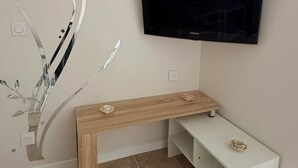 A room with a mounted TV, a wooden bench, and a white entertainment unit. - La dorée, a private room in an independent apartment (Billère)