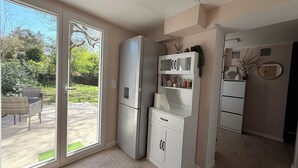 A compact kitchen with a refrigerator, a small cabinet, and a window with a view of greenery outside. - La dorée, a private room in an independent apartment (Billère)