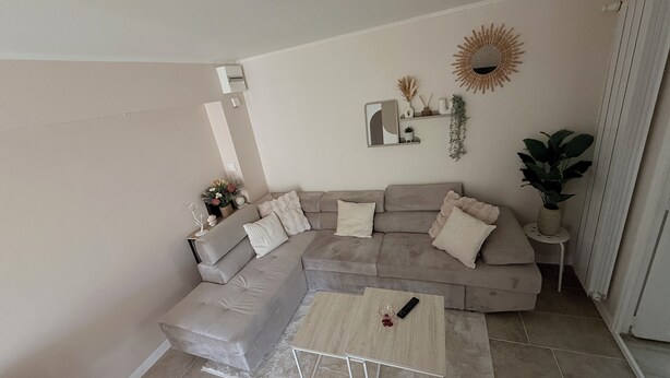 A living room with a sectional sofa, a coffee table, and a small side table with a plant. - La dorée, a private room in an independent apartment (Billère)
