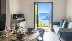 Un comedor con una mesa para cuatro personas, un sofá y un balcón con vista al mar.