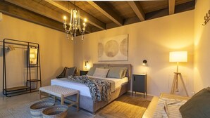 Una camera da letto con un letto, comodini, un lampadario, uno specchio, una lampada da terra e un quadro appeso al muro.