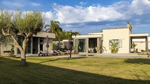 Una villa moderna con un ampio prato, posti a sedere all'aperto e una vista libera sul cielo.
