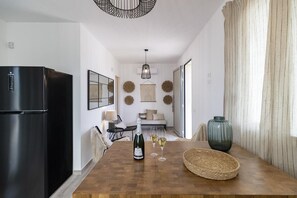 Eine moderne Küche mit einem schwarzen Kühlschrank, einem Holztisch mit Flasche und Gläsern sowie einem gewebten Korb.