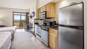 A compact kitchen with a refrigerator, microwave, stove, and dishwasher. There is a dining area with a table and chairs, and a large window offering a view. - Chula Vista Resort Studio Villa in Wisconsin Dells! Free Waterpark Passes! (Wisconsin Dells)