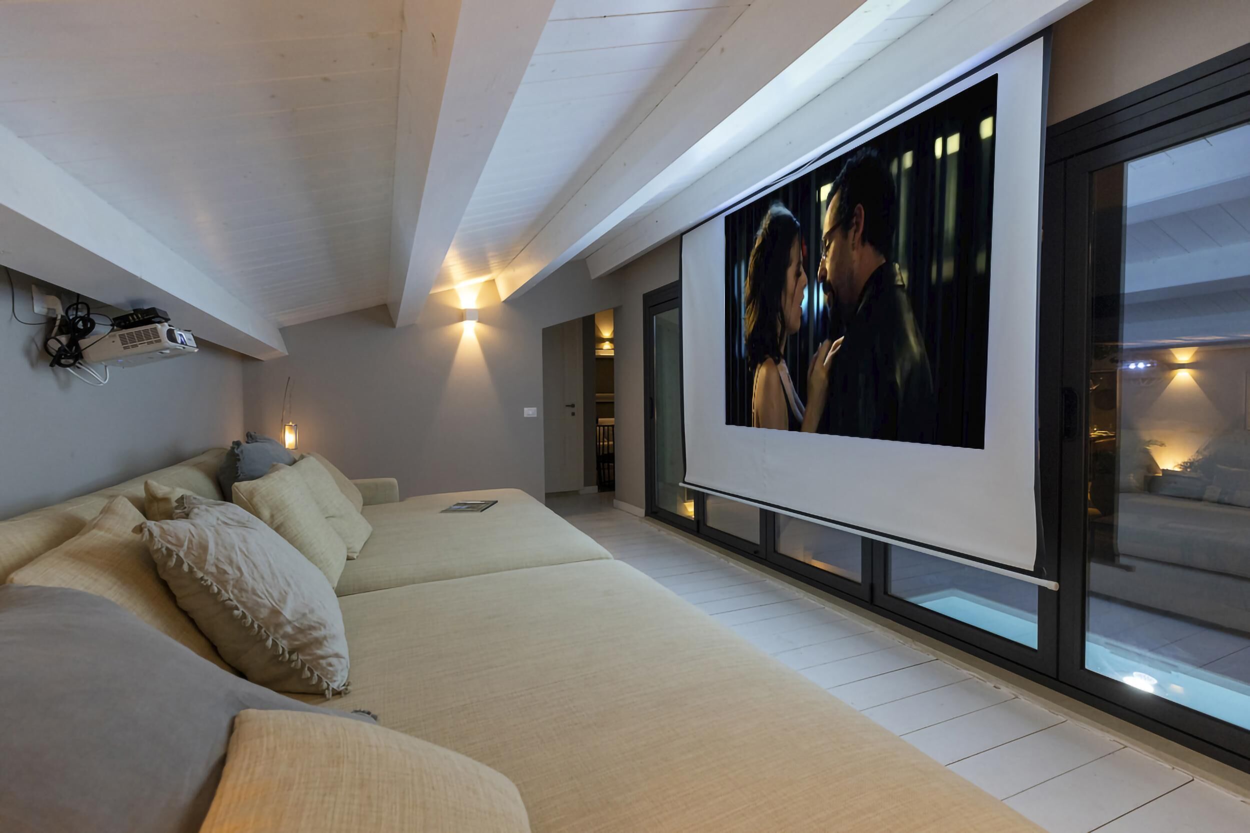 A modern living room with a large flat-screen TV, a sofa, and a glass wall.