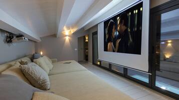 A modern living room with a large flat-screen TV, a sofa, and a glass wall.
