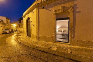 Eine Hotelschaufront mit geschlossener Tür, einem Fenster mit einem Bett und einer Straße mit parkenden Autos.