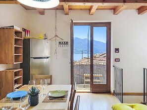 Eine Küche mit Kühlschrank, Holzregalen und einem Esstisch mit Stühlen.