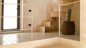 A modern interior with a staircase, a cactus, and a door leading to a bright area. - Villa Zenia - Noto - Siracusa (Noto)