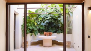 A room with a glass door, a white table with terracotta pots, and lush green plants. - Villa Zenia - Noto - Siracusa (Noto)