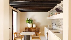 A compact kitchen with a round dining table, two chairs, a potted plant, and a built-in sink. - Villa Zenia - Noto - Siracusa (Noto)