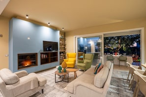 Ein modernes Wohnzimmer mit einer Couch, Sesseln, einem Couchtisch und einem Bücherregal.