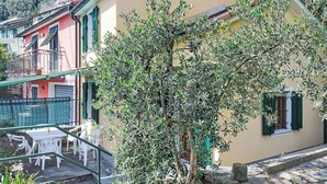 Un immeuble doté d’un balcon, d’un espace extérieur aménagé pour s’asseoir et d’un arbre devant.