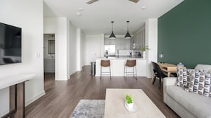 A modern kitchen with white cabinets, a central island, and pendant lighting. - Landing | Spectacular 1BD, Clubhouse, Gym (Brentwood)