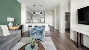 Ein modernes Wohnzimmer mit einem grauen Sofa, einem Couchtisch mit Pflanze und einem an der Wand montierten Fernseher.