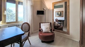 Ein Zimmer mit großem Fenster, Flachbildfernseher, Spiegel und Esstisch.