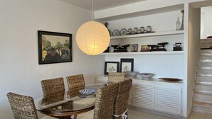 A dining area with wicker chairs, a glass table, and a hanging paper lantern.