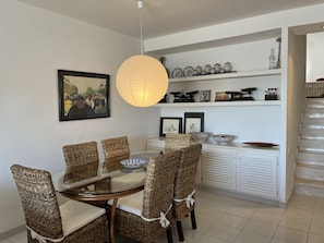 A dining area with wicker chairs, a glass table, and a hanging paper lantern. - Apartment in very front line with sea views (Fornells)