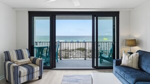 Une pièce avec vue sur l’océan, un ventilateur de plafond, un canapé, un fauteuil et une table.