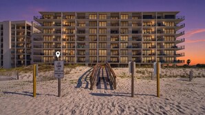 Un hôtel à plusieurs étages doté de balcons, d’un accès direct à la plage et offrant une vue sur le coucher de soleil.