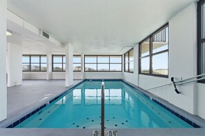 Ein Hallenbad mit klaren Fenstern, gefliestem Boden und einer Poolleiter.