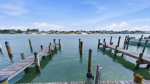 Une jetée en bois s’étendant sur une étendue d’eau calme, d’où l’on a une vue dégagée sur les maisons situées au loin.