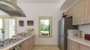 Una cocina moderna con una isla central, electrodomésticos de acero inoxidable y vistas a través de una ventana.