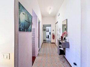 A hallway with patterned flooring, a fire extinguisher, a mirror, and a door leading to another room. - Nice apartment for 4 guests with A/C, WIFI, TV and balcony (Terracina)
