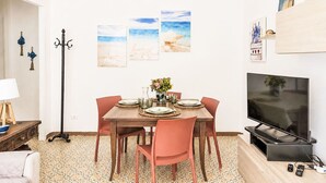 Ein Essbereich mit einem Tisch für vier Personen, einem Fernseher auf einem Schrank und Kunstwerken an der Wand.