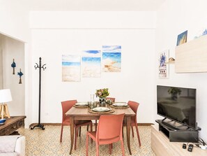 A dining area with a table set for four, a television on a stand, and artwork on the wall. - Nice apartment for 4 guests with A/C, WIFI, TV and balcony (Terracina)