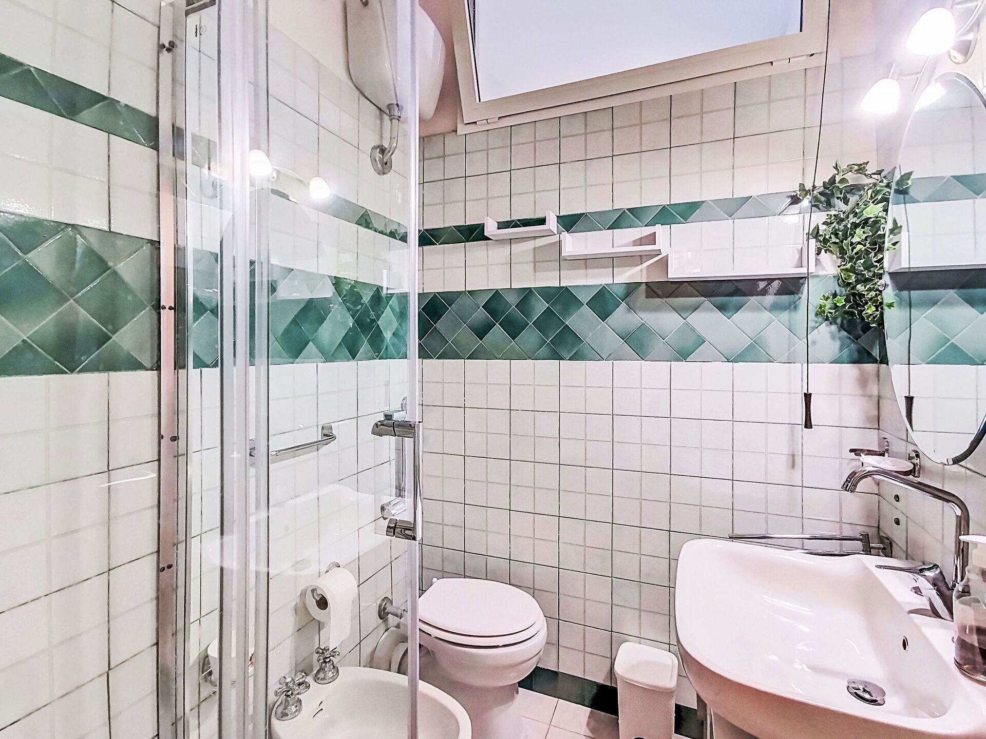 Une salle de bain avec une douche à parois de verre, des toilettes, un lavabo et un miroir.