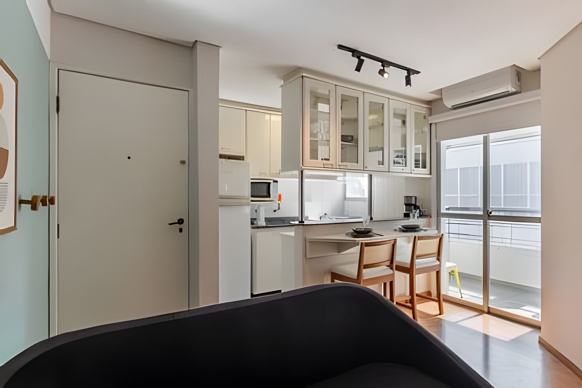 Una cocina funcional con armarios blancos, microondas y un comedor con mesa y sillas.