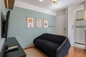 Uma sala de estar moderna com um sofá, uma televisão e obras de arte na parede.