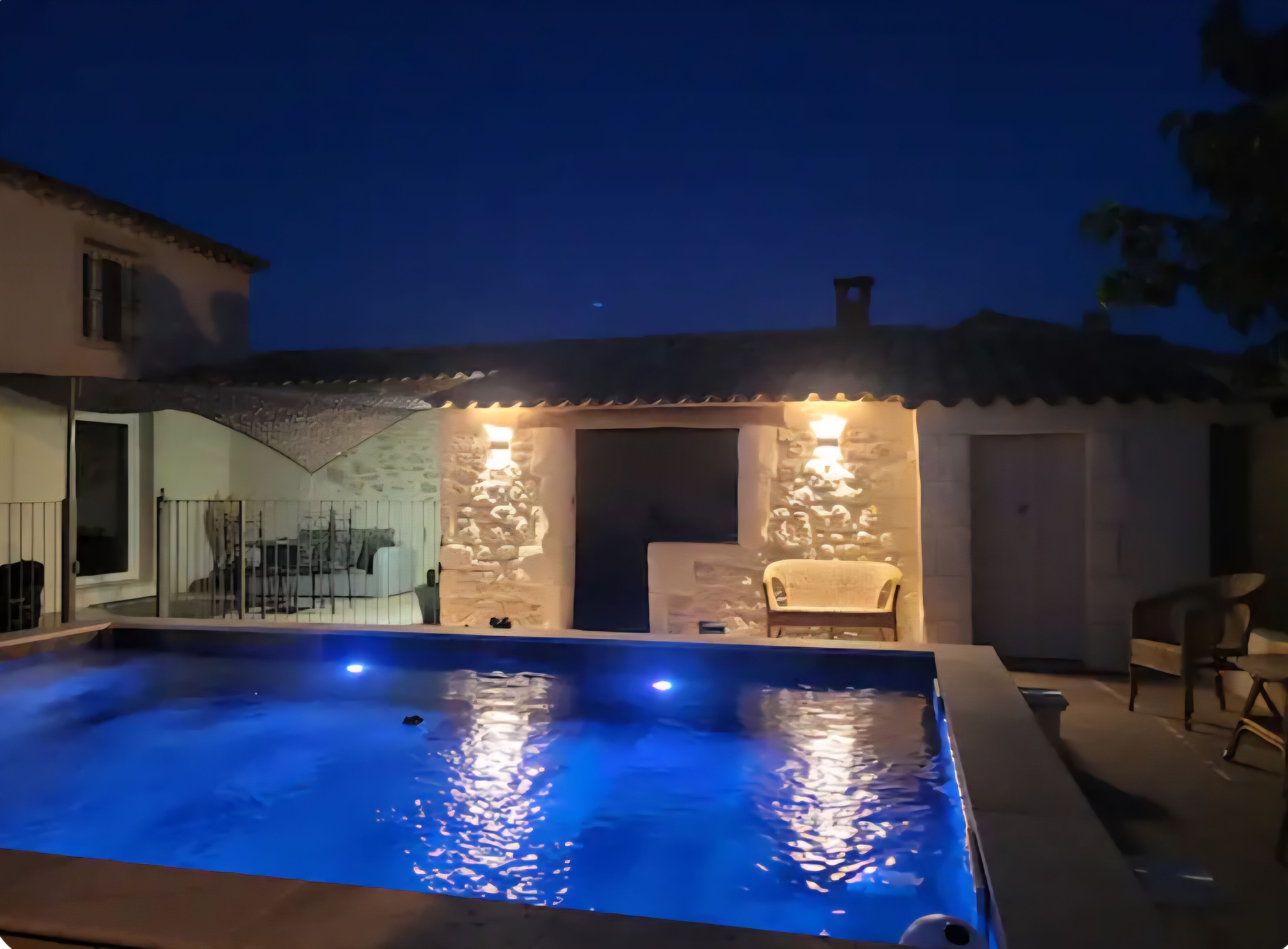A swimming pool with a stone wall and a chair.
