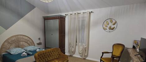 A bedroom with a bed, a sofa, a chair, a desk, a lamp, and a ceiling fan.